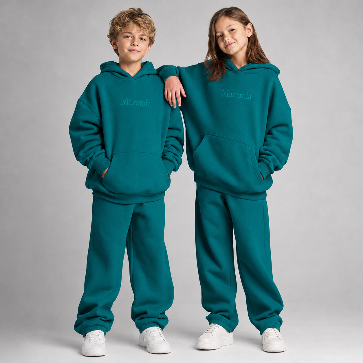 Two children wearing teal Marcmia hoodie sets