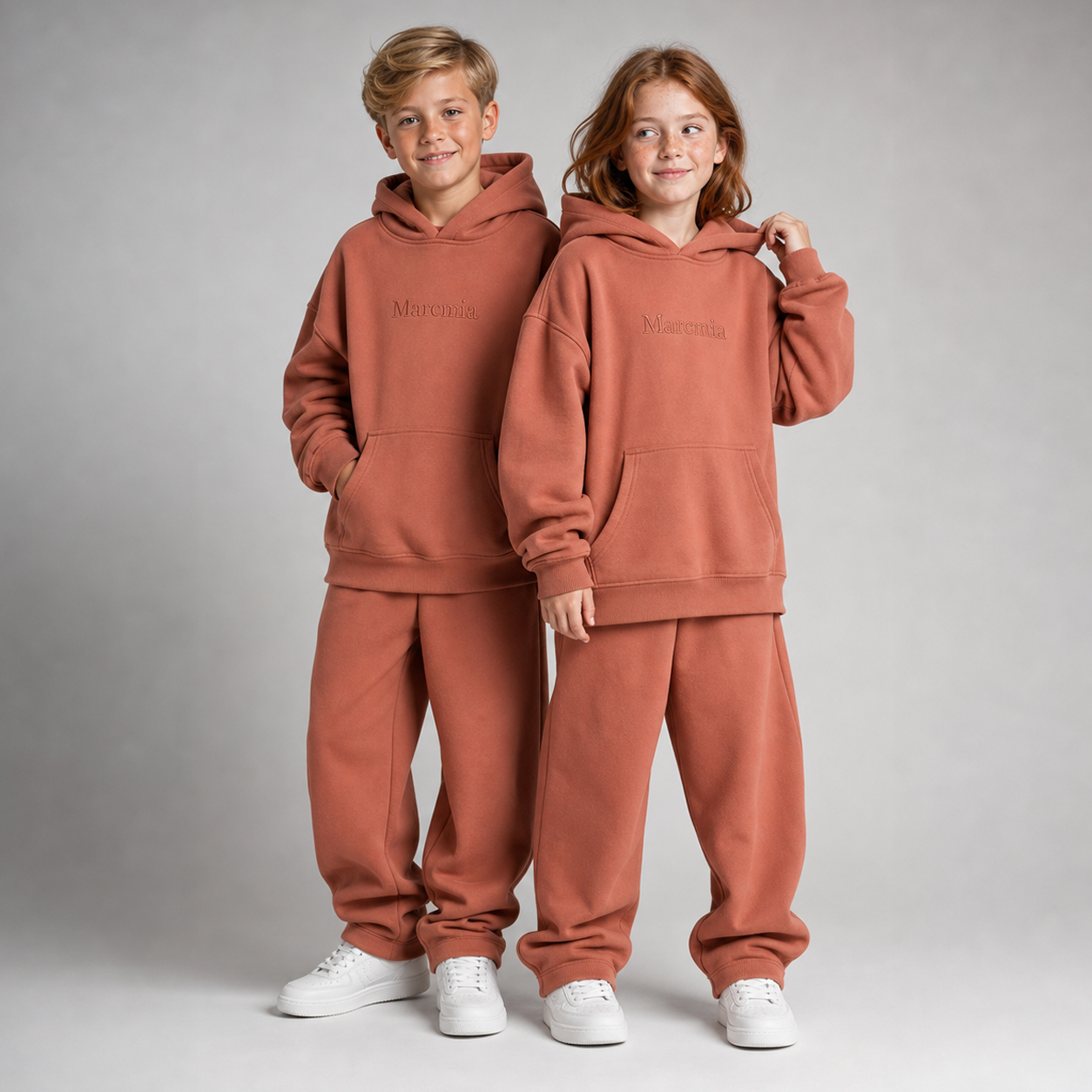 Two children wearing rust Marcmia hoodie sets