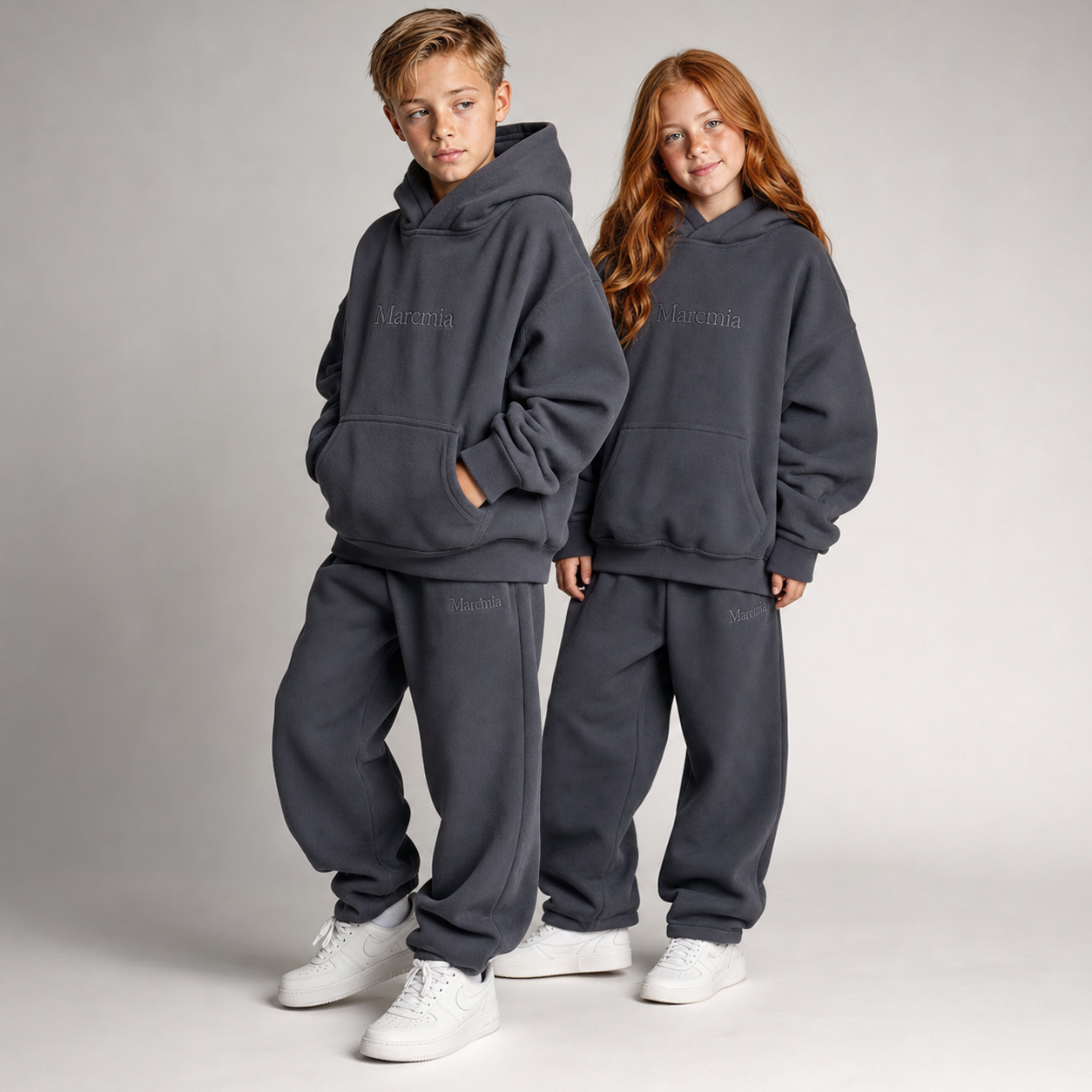 Two children wearing charcoal Marcmia hoodie sets